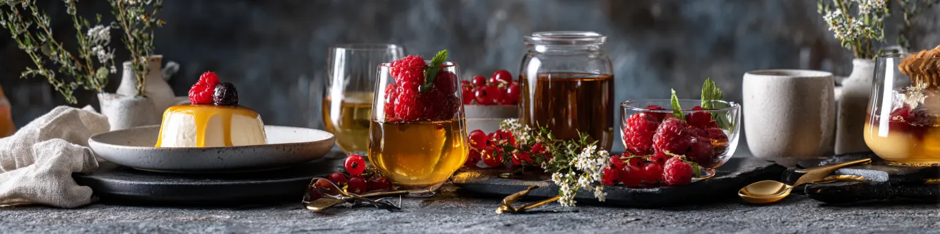 Présentation raffinée de menus gastronomiques associant miel local, fruits rouges et liqueurs andorranes dans une ambiance élégante